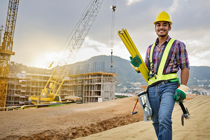 Handwerker beim tragen von Werkzeug auf einer großen Baustelle